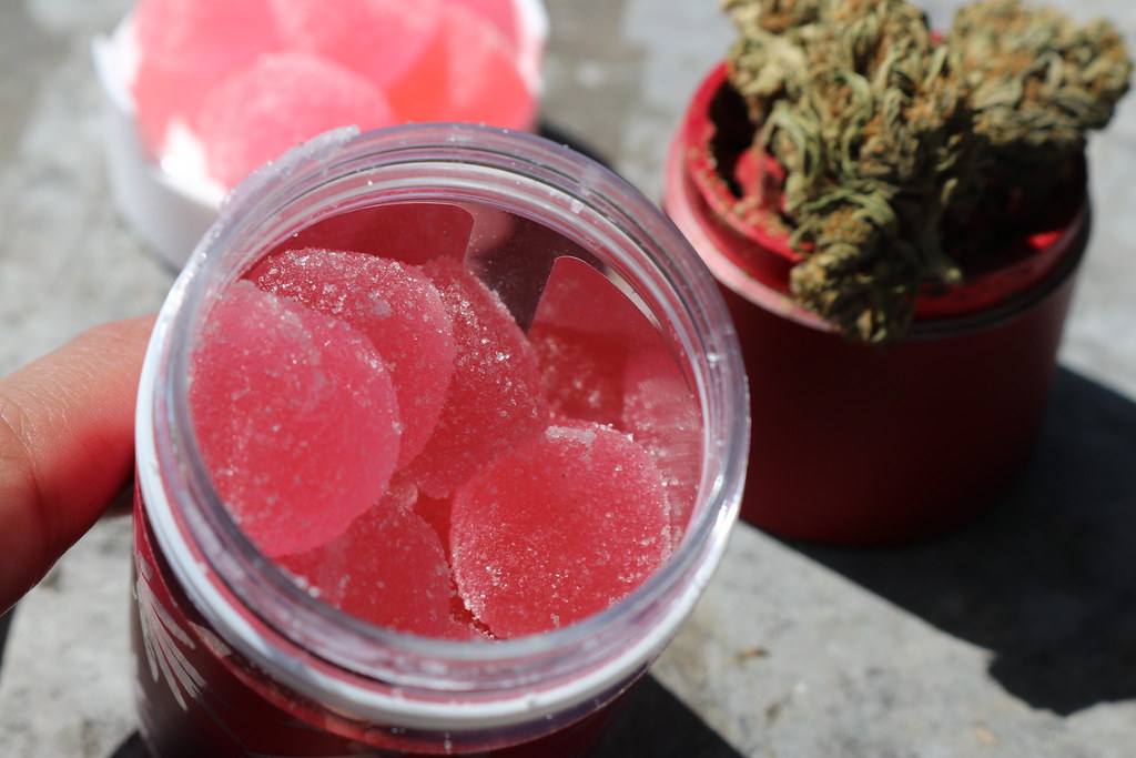 Gummies in a jar beside cannabis flower